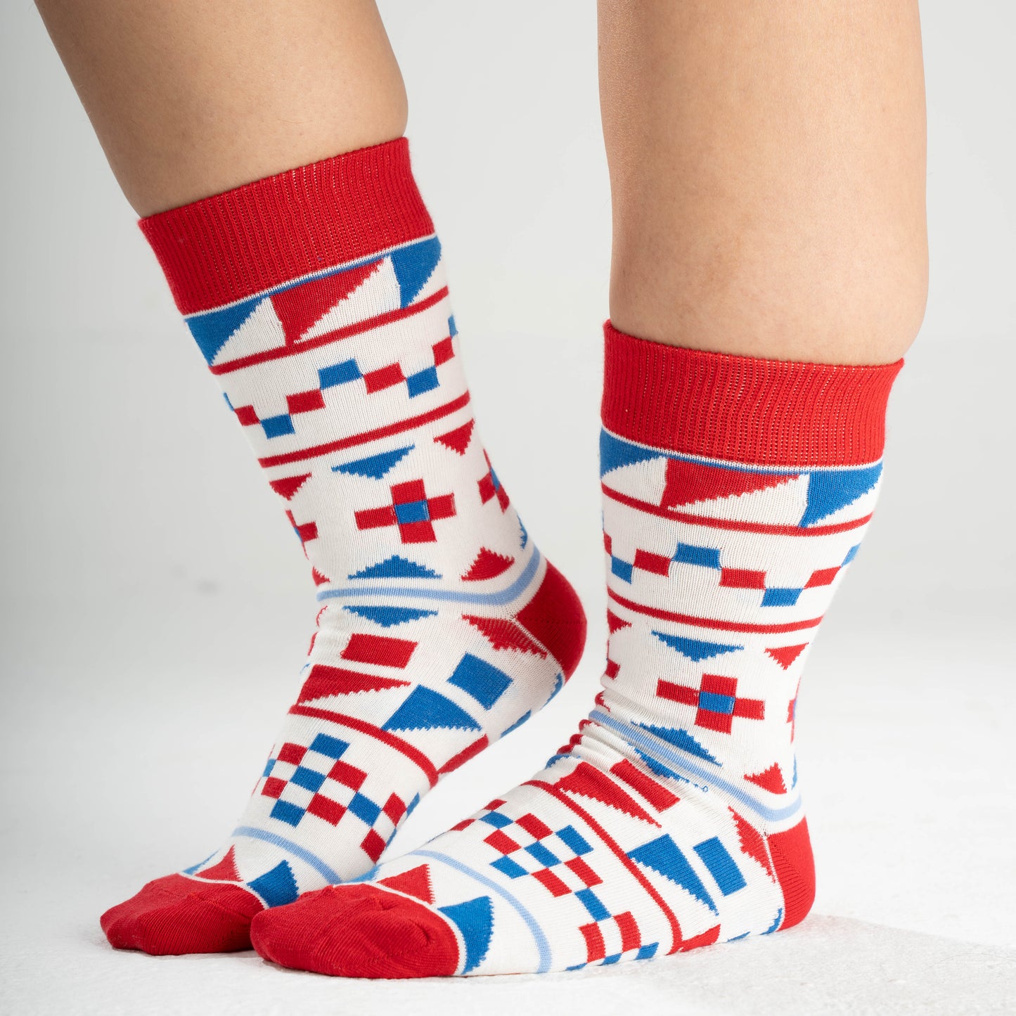 Colorful patterned socks with red cuffs on a neutral background
